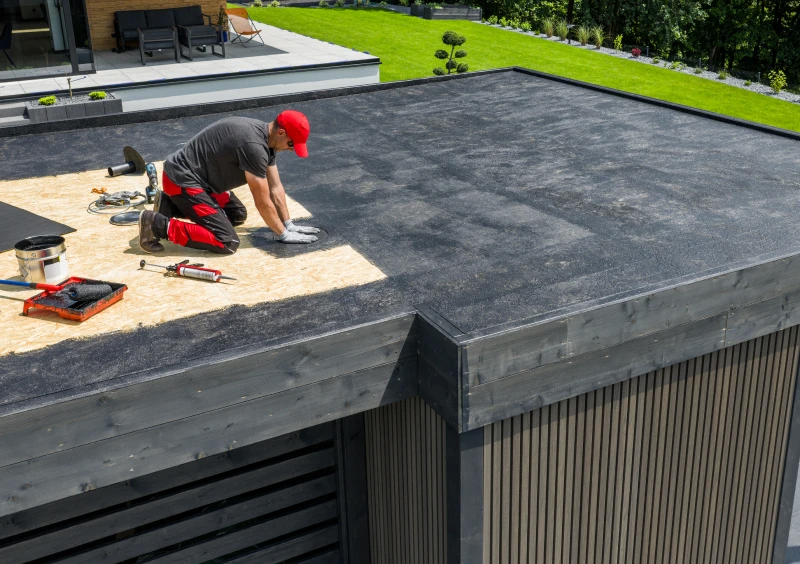 Roofer applying black roofing material